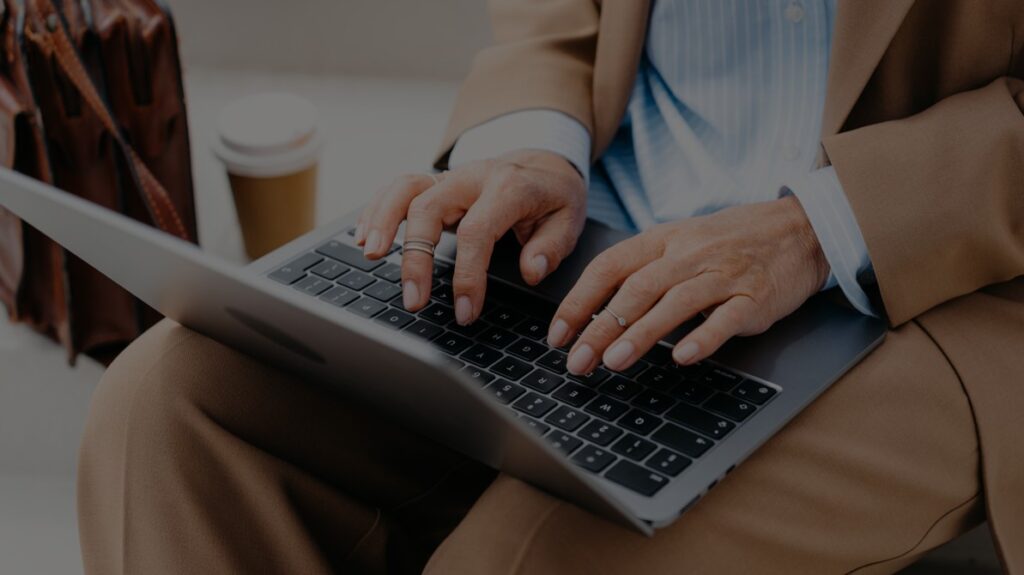 Man types at laptop outdoors