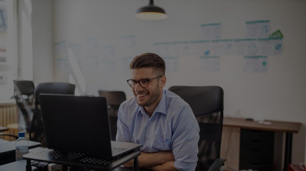 man smiling at laptop in office